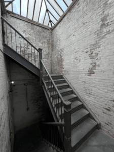 Gray and white raw brick stairwell leading to the roof.